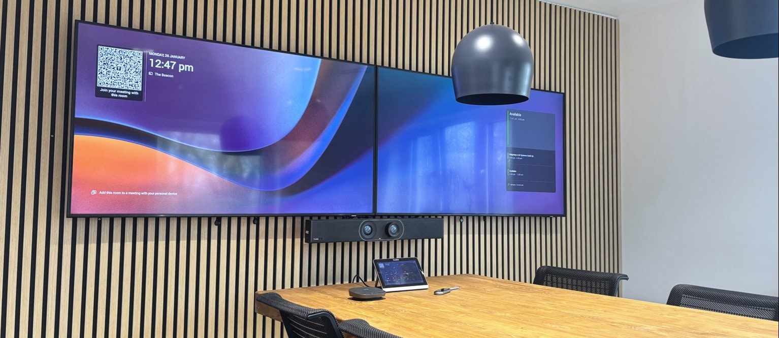 A meeting space with desk, duel screens and video conferencing equipment.